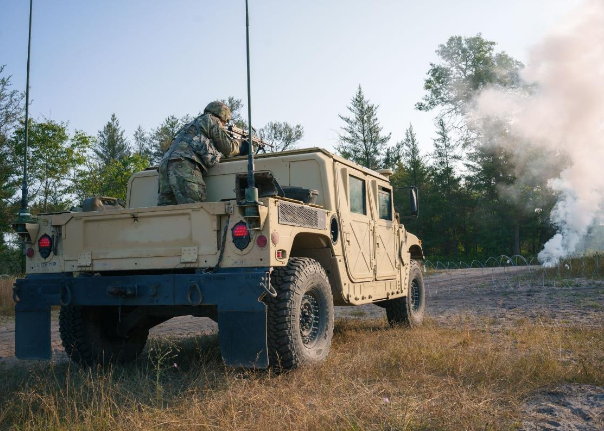 Soldier operates a mounted weapon from the turret of a Humvee during field training