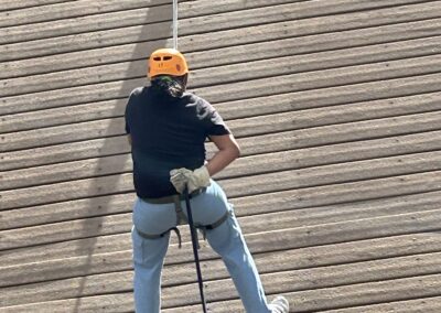 Youth participant rappels down a training wall under soldier supervision