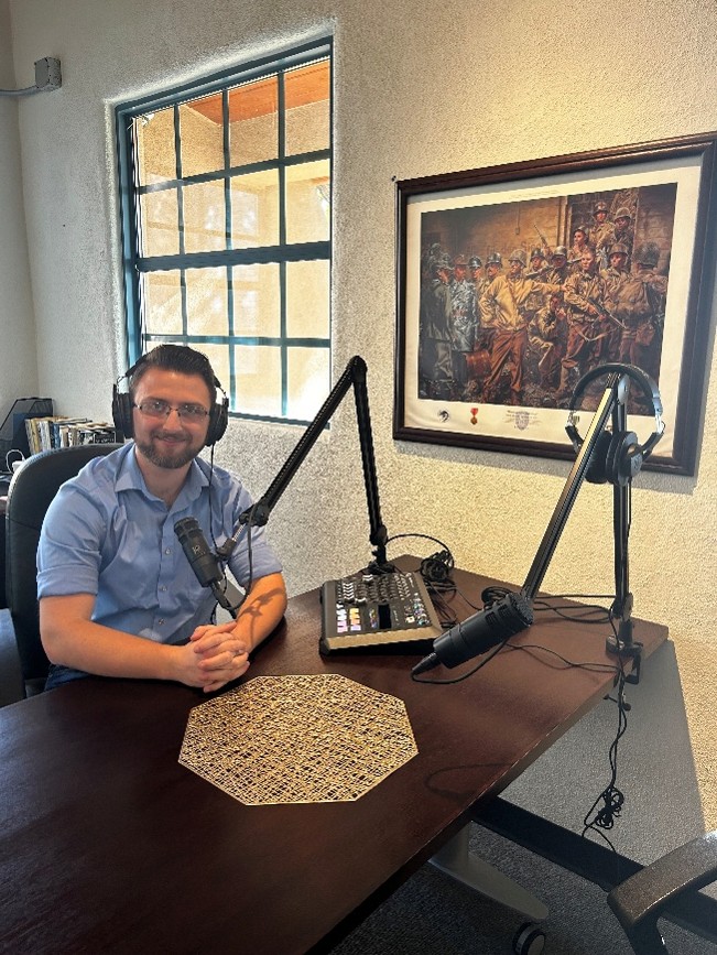 Museum staff member seated at a podcast recording desk